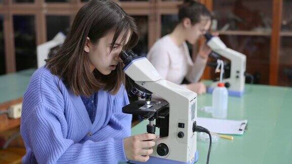 女学生在教室里使用显微镜