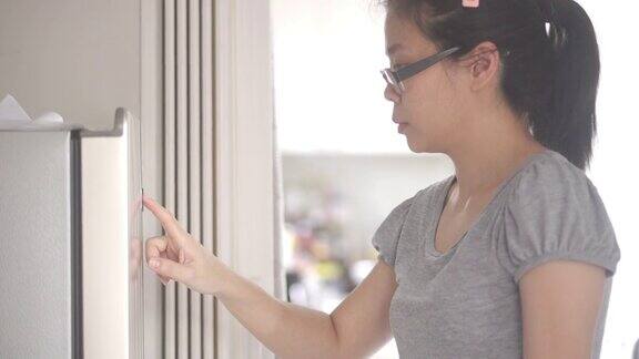 妇女阅读手册和触摸数字屏幕设置一个新的冰箱