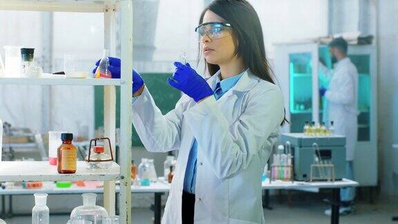 美丽的科学家女士和她的助手使用一个实验室浴盆与化学液体做实验以分析化学反应4k