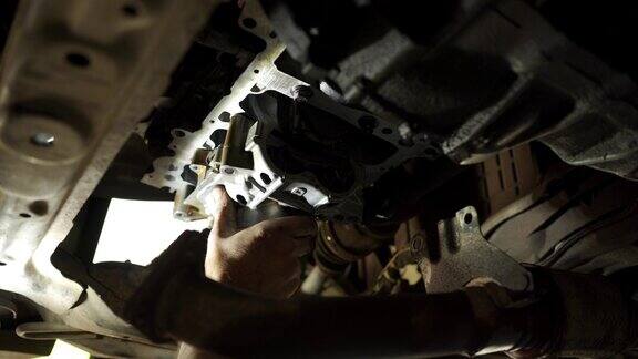 男机械师在汽车修理厂进行汽车发动机引擎盖下检查机油更换