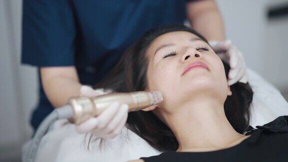 亚裔华人女美容师正在给她的病人进行微晶磨皮治疗