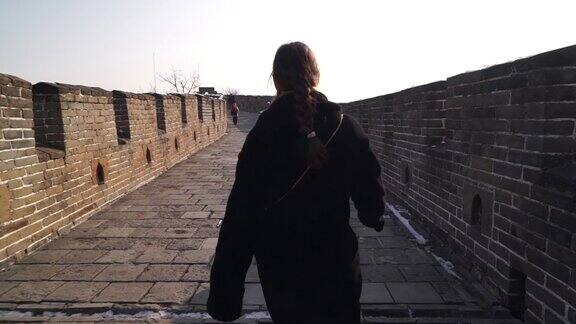 快乐的女人走在长城上在冬天日落时分从八达岭段的瞭望塔上下来