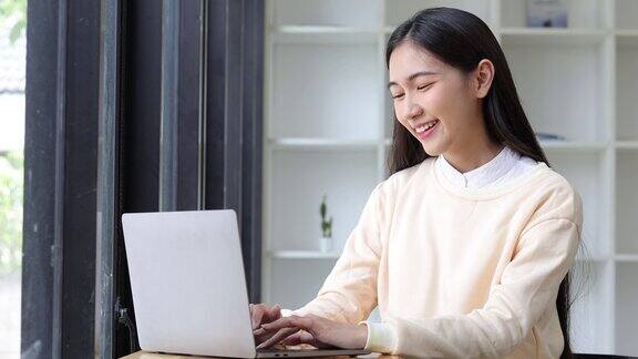 迷人的亚洲女人在家里享受打字使用笔记本电脑和搜索