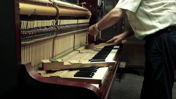 钢琴工作室钢琴工人在钢琴修理店修理一架旧钢琴4K分辨率