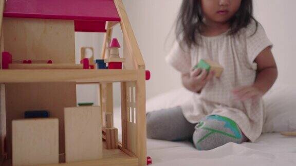 亚洲小女孩在家里玩木房子玩具