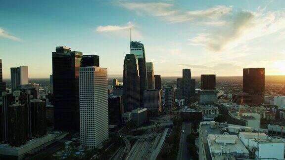 日落时分无人机飞过洛杉矶市中心摩天大楼的高速公路