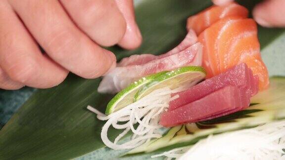 寿司厨师安排新鲜的三文鱼片和金枪鱼与青柠黄瓜和萝卜丝