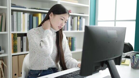 年轻的中国女学生在图书馆大学学习电脑