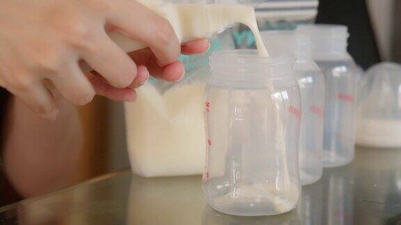 亚洲妇女用手给婴儿倒牛奶