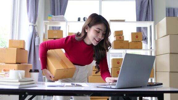 在家中工作的亚洲妇女在小企业检查在线订单准备将盒装物品送到客户手中