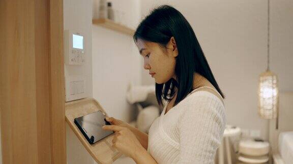 亚洲女性使用家用自动化和智能家居技术开空调、灯和空调
