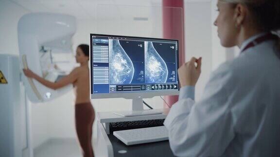 医院放射科病房的电脑屏幕:美丽的多民族成年妇女站在半裸乳房接受乳房x光检查程序屏幕显示乳腺致密组织的乳房x光扫描