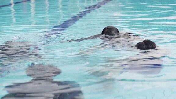 亚洲华人游泳教练在教他的学生在游泳池呼吸练习
