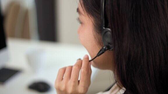 近smiley亚洲商业女接待员戴耳机视频会议电话在电脑上通过网络摄像头在网上聊天客户支持服务