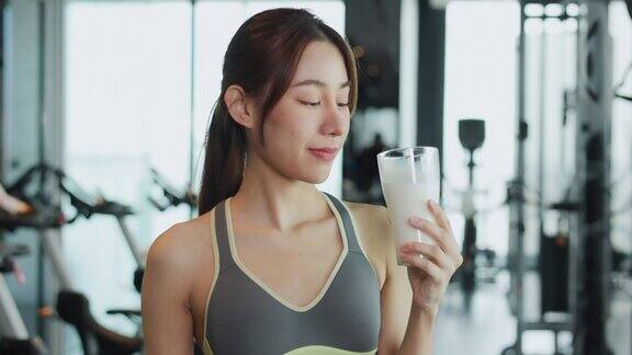 迷人的健美亚洲女人完成锻炼和喝蛋白质牛奶奶昔维生素训练后健身健康的生活方式