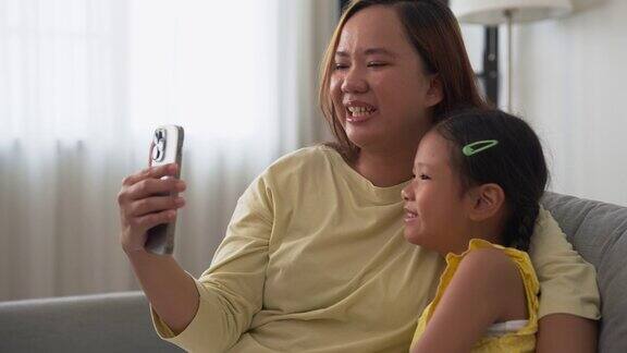 欢快的家庭亚洲母亲和女儿用智能手机进行视频通话