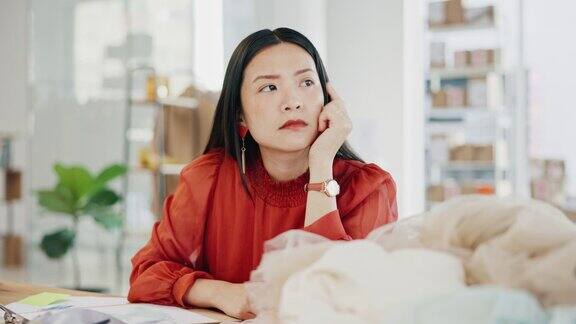女性或时装设计师在制作工作室思考想法灵感或计划服装生产亚洲人在纺织、裁缝业务方面考虑创造性或深思熟虑的策略