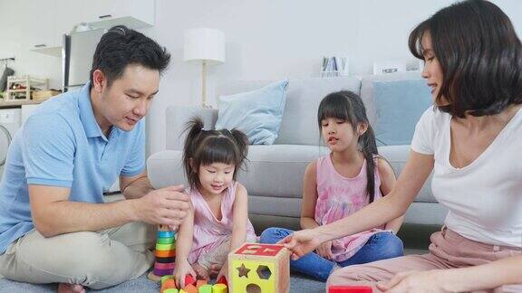 亚洲幸福家庭坐在地板上在客厅里一起玩玩具漂亮的父母和父母花时间和年轻的小女孩在家里家庭活动关系概念