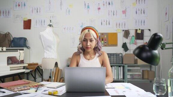 亚洲女时装设计师在她的工作室里用笔记本电脑画草图