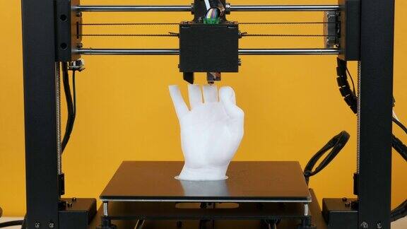 3D打印机打印模型手由白色塑料制成的黄色背景特写打印头打印机工作平台运动清晰现代3D打印技术塑料线轴