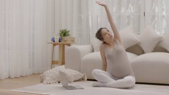 怀孕的母亲为了她未出生的孩子的健康练习瑜伽呆在家里
