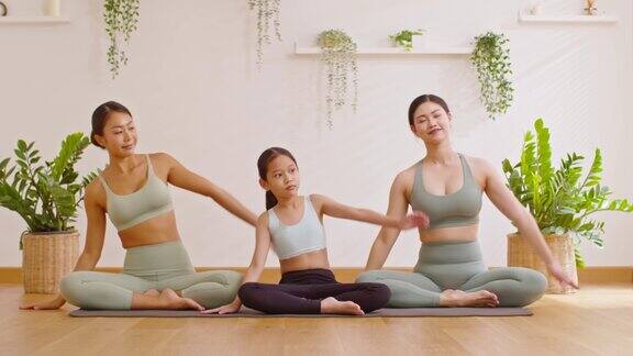 健康的夫妇妈妈和小女孩做伸展肌肉热身瑜伽教练在家里私人瑜伽班辅导孩子摆姿势与母女在温暖的地方进行呼吸练习