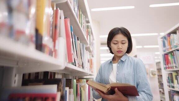 亚洲女大学生在大学校园图书馆的藏书与课本阅读