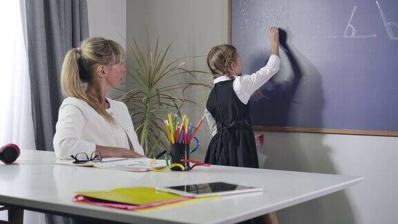 勤奋的白人女学生转向黑板和写粉笔成年妇女坐在桌旁教孩子教育小学生电影4kProRes总部