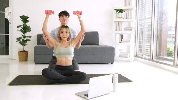 一对年轻的亚洲夫妇正在家里做健身训练