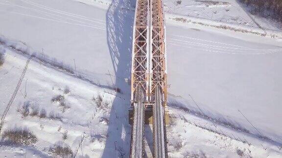无人机观察火车在冬季河上的铁路桥上移动火车交通在悬索桥上通过冻结的河流空中景观