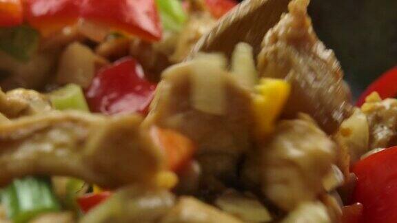 在锅里用抹刀搅拌胡椒、芹菜、鸡肉、洋葱和蘑菇