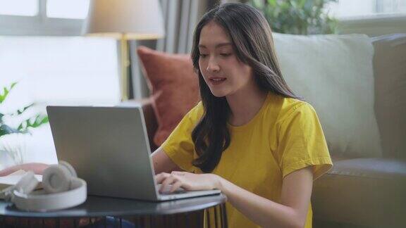 年轻迷人的亚洲女性在家里工作用手提电脑检查业务数据图表规划报告休闲放松在客厅沙发上居家隔离