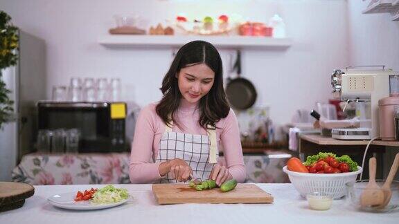 年轻的亚洲人在厨房里准备切蔬菜做沙拉喜欢烹饪食物