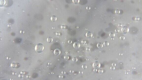 透明的液体凝胶背景清晰的血清质地运动、旋转带有气泡的美容护肤产品样品前视图微距镜头