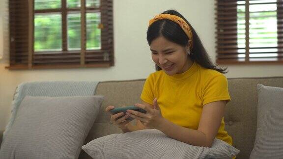 亚洲妇女坐在沙发上使用手机