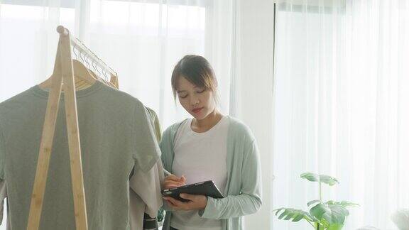 年轻的亚洲女卖家在网上商店工作使用平板电脑在家里检查订单小企业主