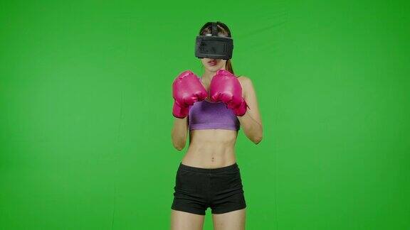 健身女性拳击使用VR头盔在绿色屏幕上聚焦色度键技术增强现实亚洲妇女用于图形覆盖和剪切的目的