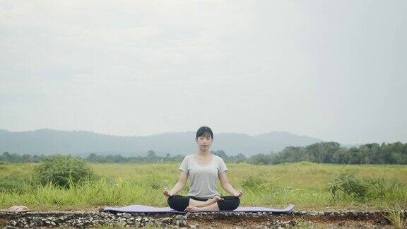 美丽的亚洲白人女性坐在冥想姿势姿势瑜伽体式平衡在美丽的山景上午