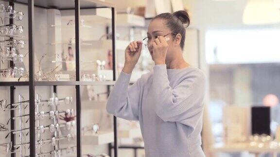 成熟的妇女在商店选购眼镜