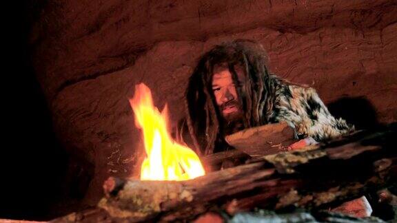 史前穴居人在他的洞穴中看着火和他的矛