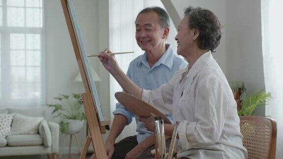 一位上了年纪的男子和他的亚洲妻子在一起愉快地画水彩画