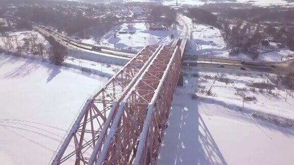 悬索桥通过冬季河流和汽车交通在积雪公路鸟瞰图铁路桥用于在冰冻的河流上移动的无人机视图