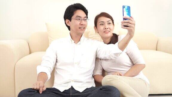幸福的亚洲夫妇在家里客厅用智能手机与朋友和家人进行视频通话居家隔离保持社交距离扬已婚观念