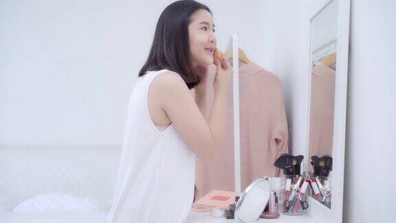 美丽的亚洲女人使用粉化妆前镜快乐的女性使用美容化妆品提高自己准备在卧室在家里工作生活方式女性在家放松