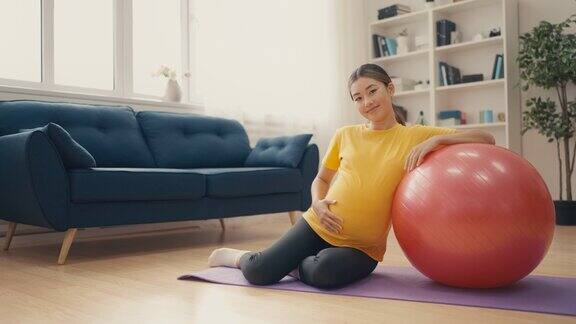 亚洲妇女的肖像与婴儿凸在家健身健康怀孕