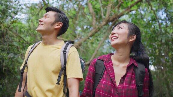 年轻的亚洲男人和女人朋友一起在森林里旅行情侣们在大自然中感受清新和放松看着窗外的风景然后带着幸福和乐趣继续散步