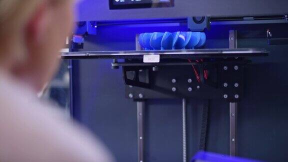 一名女性白种工程师在3D打印机内俯瞰模型的建造过程