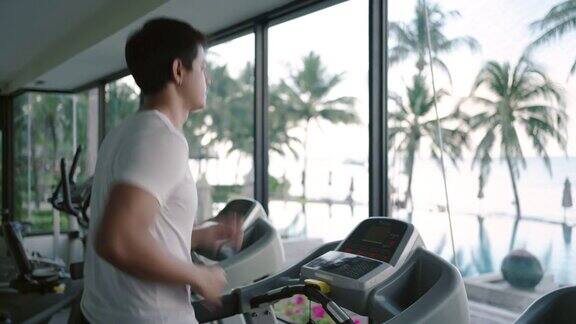 一名亚洲男子早上在度假健身中心的跑步机上锻炼