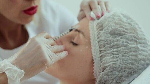 美容师双手戴着手套在女性皮肤上进行面部衰老注射一个女人得到美容美容程序