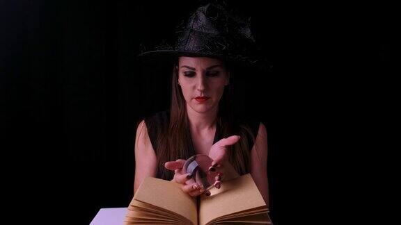 美丽的女人穿着黑色的女巫服装和帽子手里拿着一个透明的魔法球和变戏法万圣节的节日聚会